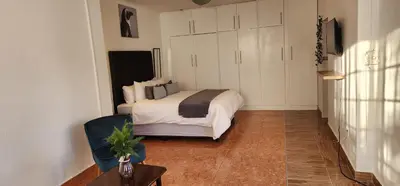 a bedroom with a bed and a table in a room at Khayelihle Guest house in Benoni