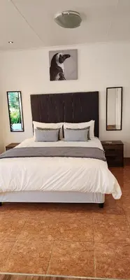 a bedroom with a large bed with a black headboard at Khayelihle Guest house in Benoni