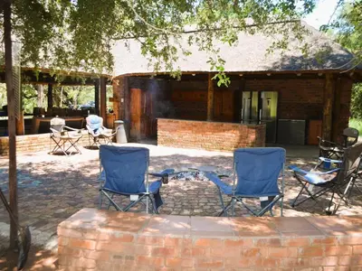 a patio with two blue chairs and a brick building at Masungulo Lodge in Modimolle