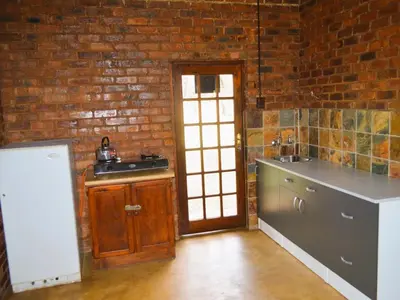 a kitchen with a sink and a brick wall at Masungulo Lodge in Modimolle