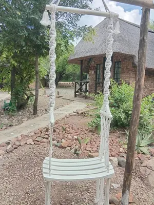 a white swing in front of a building at Elephant Memories Glamping Safari Tents and more in Marloth Park