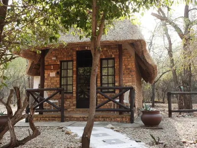 a small brick building with a grass roof at Elephant Memories Glamping Safari Tents and more in Marloth Park