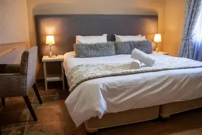 a bedroom with a large bed and a desk with a chair at Casa de la Presa 3 in Polokwane