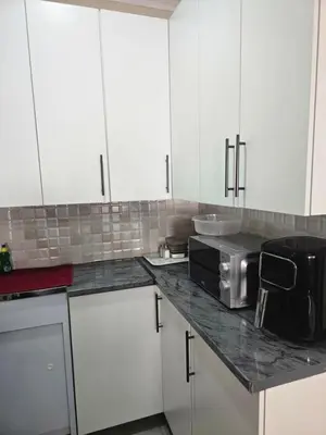 a kitchen with white cabinets and a microwave on a counter at Peshline Guest House Unit 2 in Ermelo