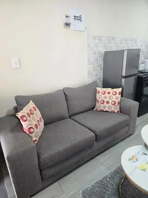 a gray couch with two pillows in a living room at Peshline Guest House Unit 2 in Ermelo