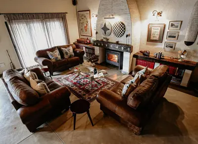 a living room with leather furniture and a fireplace at Phelwana Game Lodge in Hoedspruit