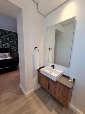 a bathroom with a sink and a mirror at GreenLeaf Stays - Menlyn Maine Apartments in Pretoria