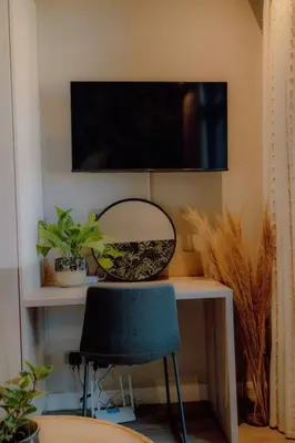 a desk with a chair and a television on a wall at GreenLeaf Stays - Menlyn Maine Apartments in Pretoria