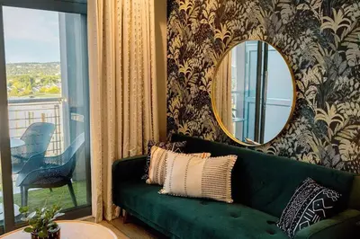 a green couch in a living room with a mirror at GreenLeaf Stays - Menlyn Maine Apartments in Pretoria