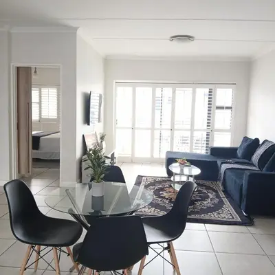 a living room with a blue couch and a glass table at The Blyde 2 bedrooms Luxe Marvelous Apartment in Pretoria