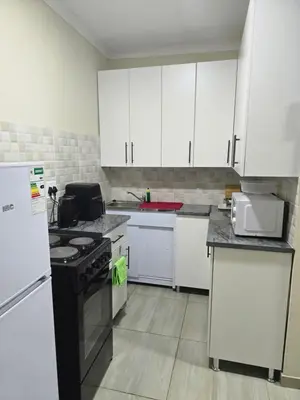 a kitchen with white cabinets and a black stove top oven at Peshline Guest House Unit 3 in Ermelo