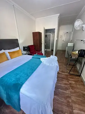 a large white bed in a room with a table at Creekside Guest House Middelburg in Middelburg