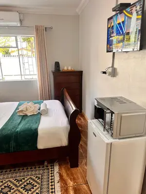 a bedroom with a bed and a microwave on a refrigerator at Creekside Guest House Middelburg in Middelburg