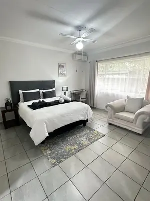 a bedroom with a large bed and a couch at Creekside Guest House Middelburg in Middelburg