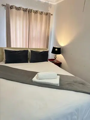 a bedroom with a white bed with a window at Creekside Guest House Middelburg in Middelburg