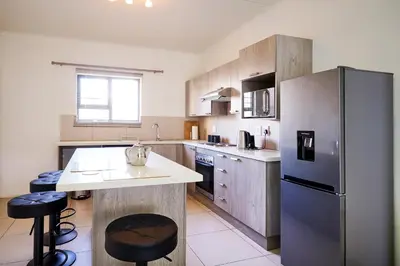 a large kitchen with a stainless steel refrigerator at Cozy Escape: 2 BR Apt. Sleeps 4 in Midrand
