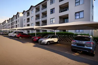 a row of cars parked in front of a building at Cozy Escape: 2 BR Apt. Sleeps 4 in Midrand