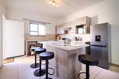 a kitchen with a counter and stools in it at Cozy Escape: 2 BR Apt. Sleeps 4 in Midrand