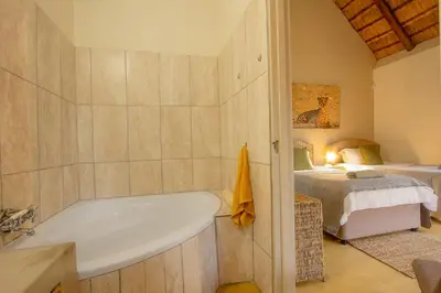 a bathroom with a bath tub next to a bed at Sweet Thorn House MARLOTH PARK in Marloth Park