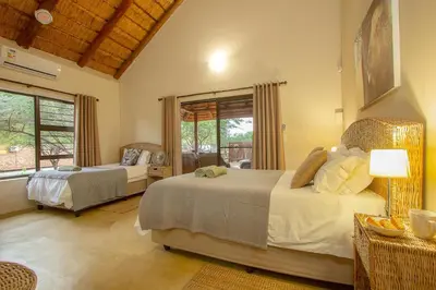 a bedroom with two beds and a large window at Sweet Thorn House MARLOTH PARK in Marloth Park