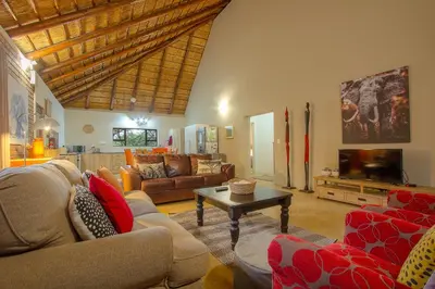 a living room with couches and a tv and a table at Sweet Thorn House MARLOTH PARK in Marloth Park