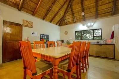 a dining room with a wooden table and chairs at Sweet Thorn House MARLOTH PARK in Marloth Park