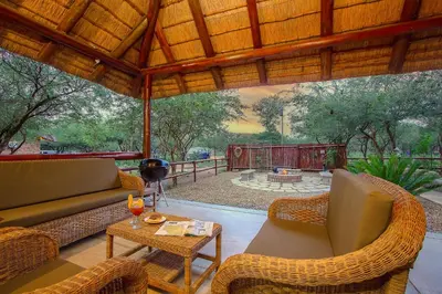 a patio with a couch and chairs and a table at Sweet Thorn House MARLOTH PARK in Marloth Park