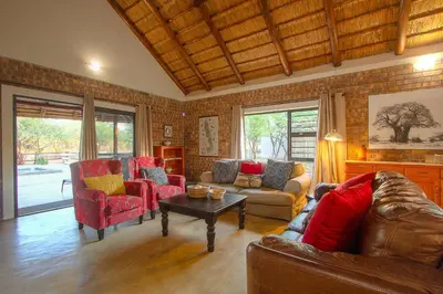 a living room with a couch and chairs and a table at Sweet Thorn House MARLOTH PARK in Marloth Park
