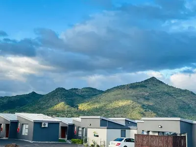 a row of houses with mountains in the background at Maphuthi River Lodge in Ga-Manapane