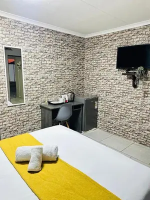 a bedroom with a bed and a desk and a tv at Maphuthi River Lodge in Ga-Manapane