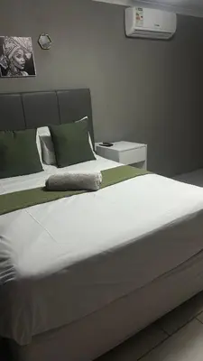 a large white bed with green and white pillows at Maphuthi River Lodge in Ga-Manapane
