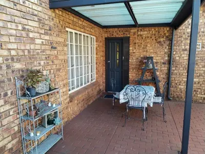 a patio with a brick wall and a table and chairs at Jan's Cottage in Centurion