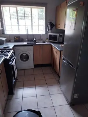 a kitchen with a refrigerator and a washing machine at Jan's Cottage in Centurion