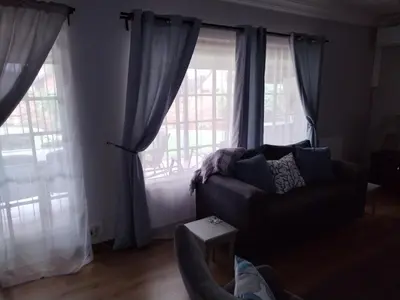 a living room with a couch and two large windows at Jan's Cottage in Centurion