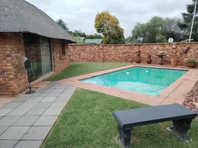 a swimming pool in a yard next to a brick building at Jan's Cottage in Centurion