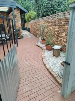 a brick walkway with a fence next to a brick wall at Jan's Cottage in Centurion