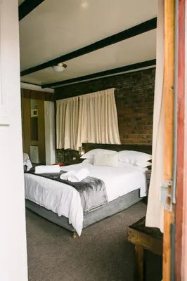 a bedroom with two beds and a brick wall at Pennylane Guest House in Ermelo