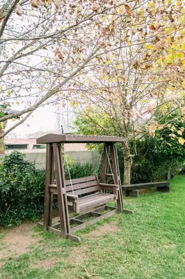 a wooden bench sitting in the grass under a tree at Pennylane Guest House in Ermelo