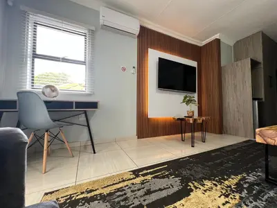 a living room with a desk and a tv at Villameyer Lodge in Pretoria