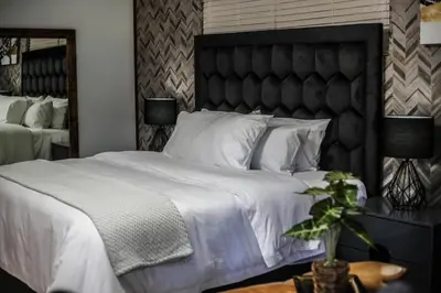 a bedroom with a large bed with white sheets and pillows at Villameyer Lodge in Pretoria