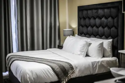 a bedroom with a large bed with white sheets and pillows at Villameyer Lodge in Pretoria