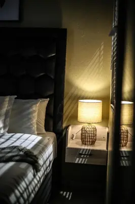 a bedroom with a bed and a lamp on a night stand at Villameyer Lodge in Pretoria