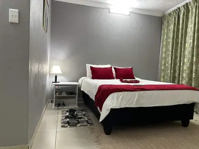 a bedroom with a large bed with red pillows at Monavy Riverside Hotels in Tzaneen in Lenyenye