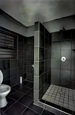a black bathroom with a toilet and a shower at Monavy Riverside Hotels in Tzaneen in Lenyenye