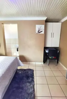 a bedroom with a bed and a blue rug at Monavy Riverside Hotels in Tzaneen in Lenyenye