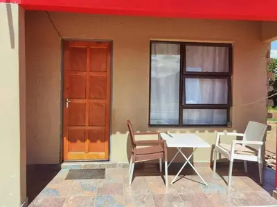 a house with a table and chairs and a window at Monavy Riverside Hotels in Tzaneen in Lenyenye