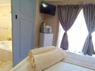 a bathroom with a chair in front of a window at OR Tambo Stay Unit 4 in Boksburg