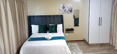 a bedroom with a large bed with green pillows at Risima guest house in Kempton Park