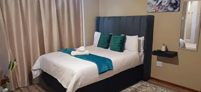 a bed with a blue headboard in a room at Risima guest house in Kempton Park