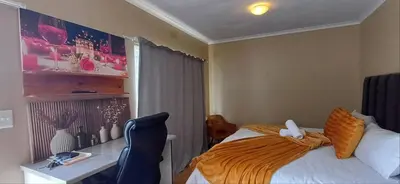 a bedroom with a bed and a desk and a desk at Risima guest house in Kempton Park